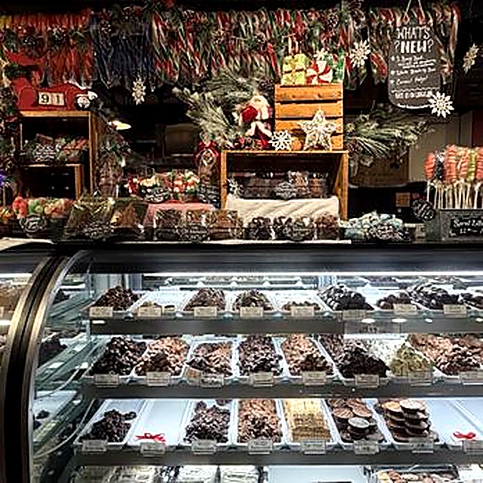 The Olde World Fudge case dressed for Christmas, trays of bark and chocolates below